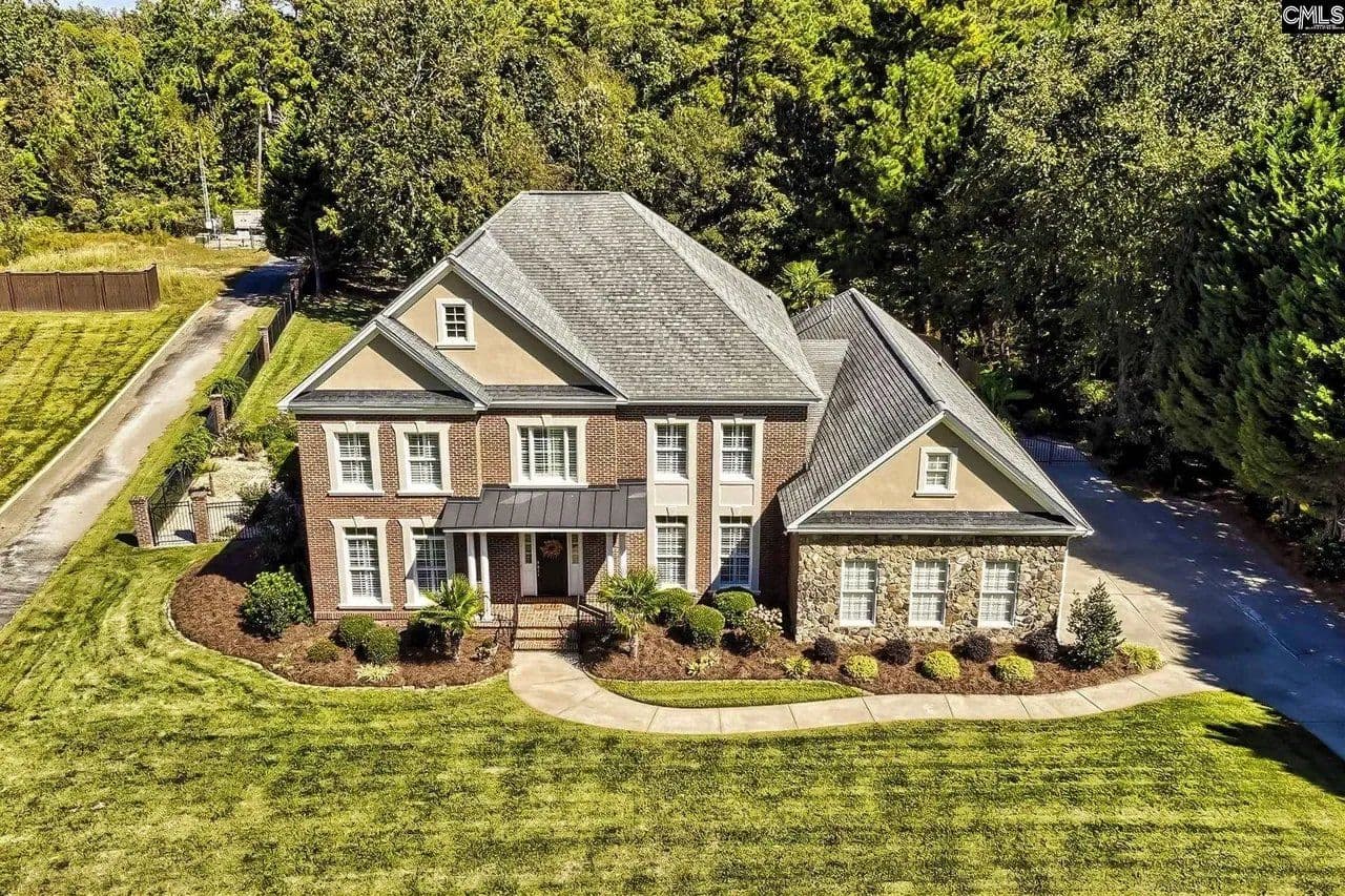 Elevated aerial of a two-story brick home with a manicured lawn