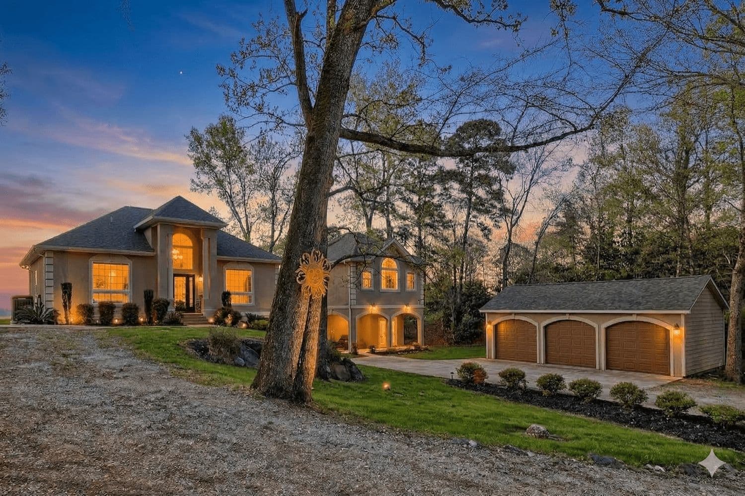 Modern home at twilight with warm lights on a gravel driveway
