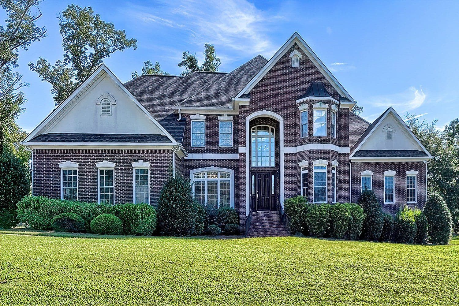 Two-story red brick home with white-trimmed entrance