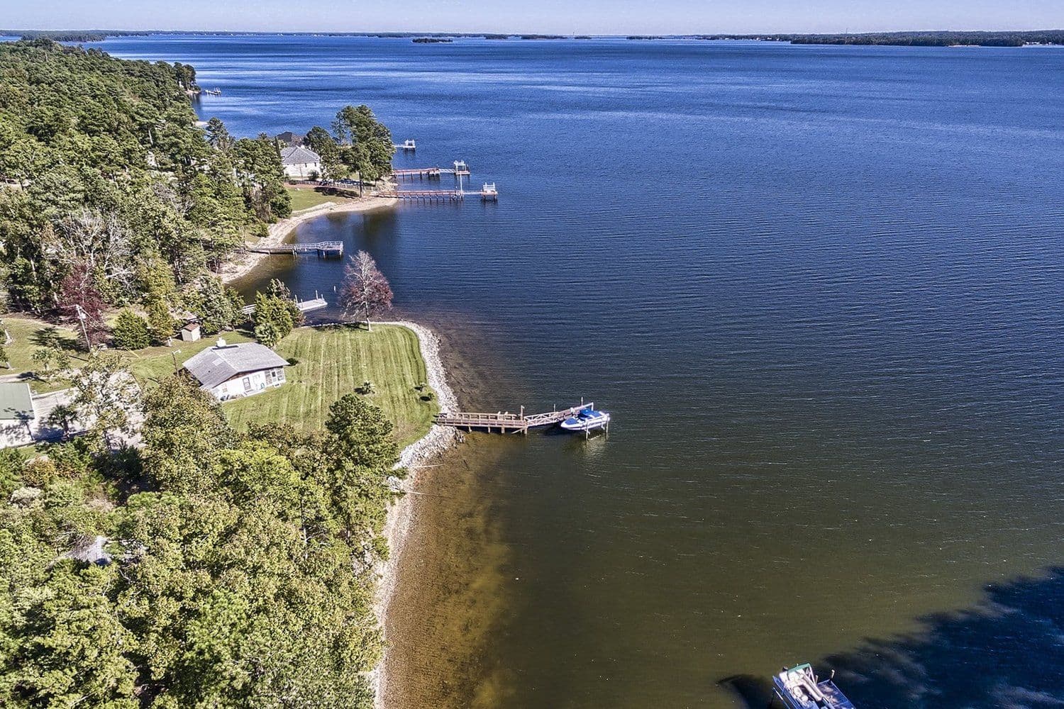Aerial of a lake shoreline with several wooden docks and lush trees