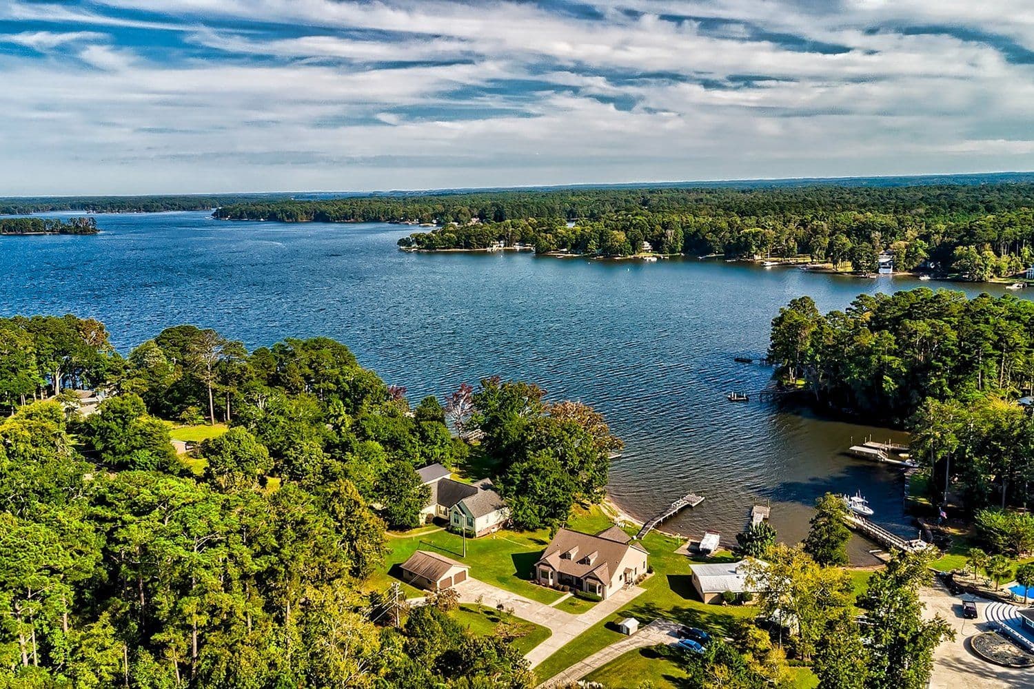 Aerial of a tree-lined lake coastline with several houses