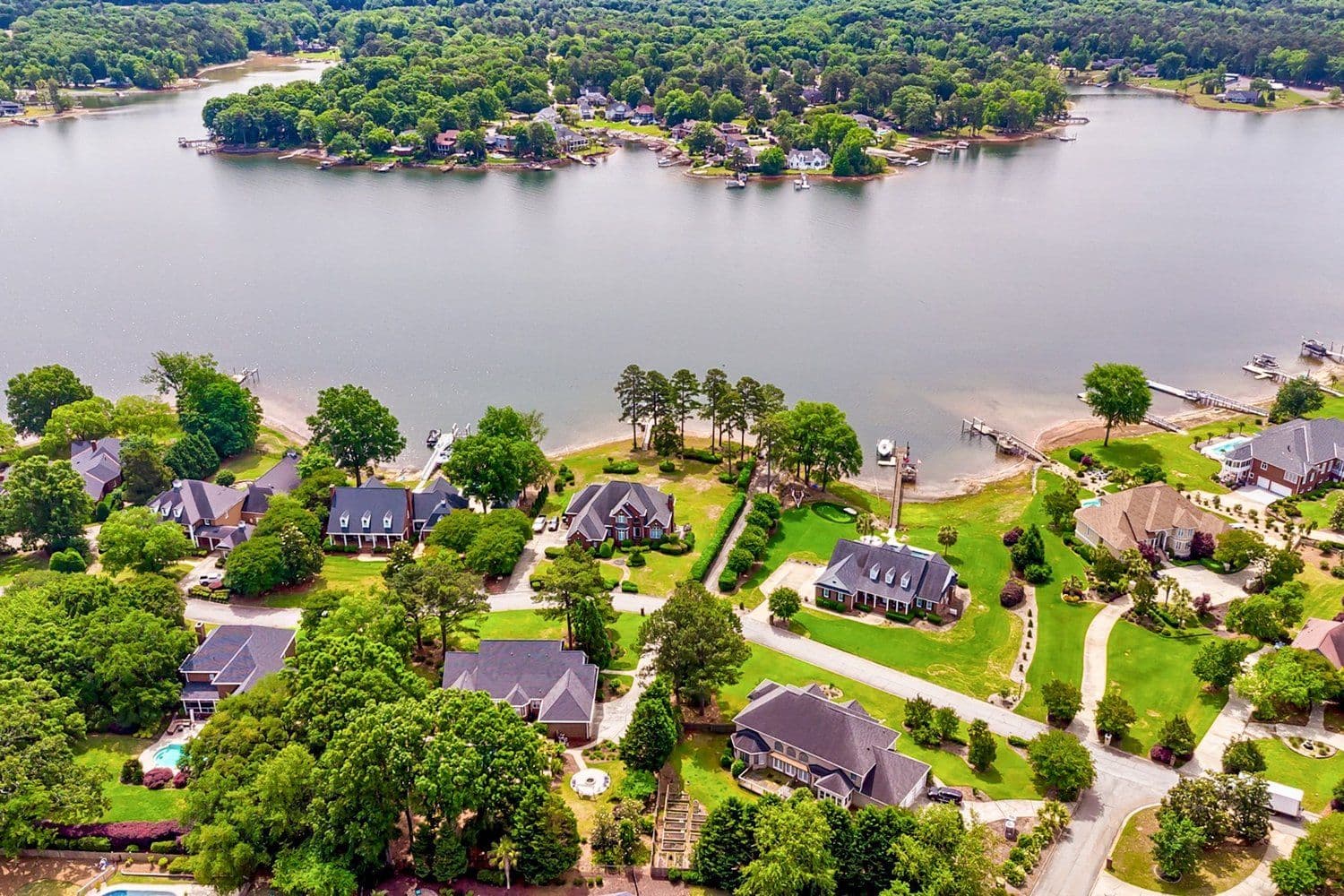 Aerial view of a lakeside neighborhood with homes and mature trees along the shore