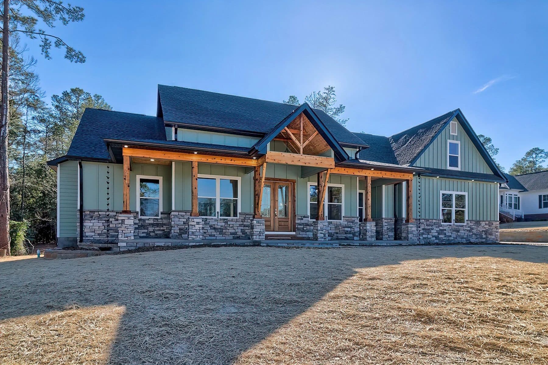 A sage farmhouse with a stone porch