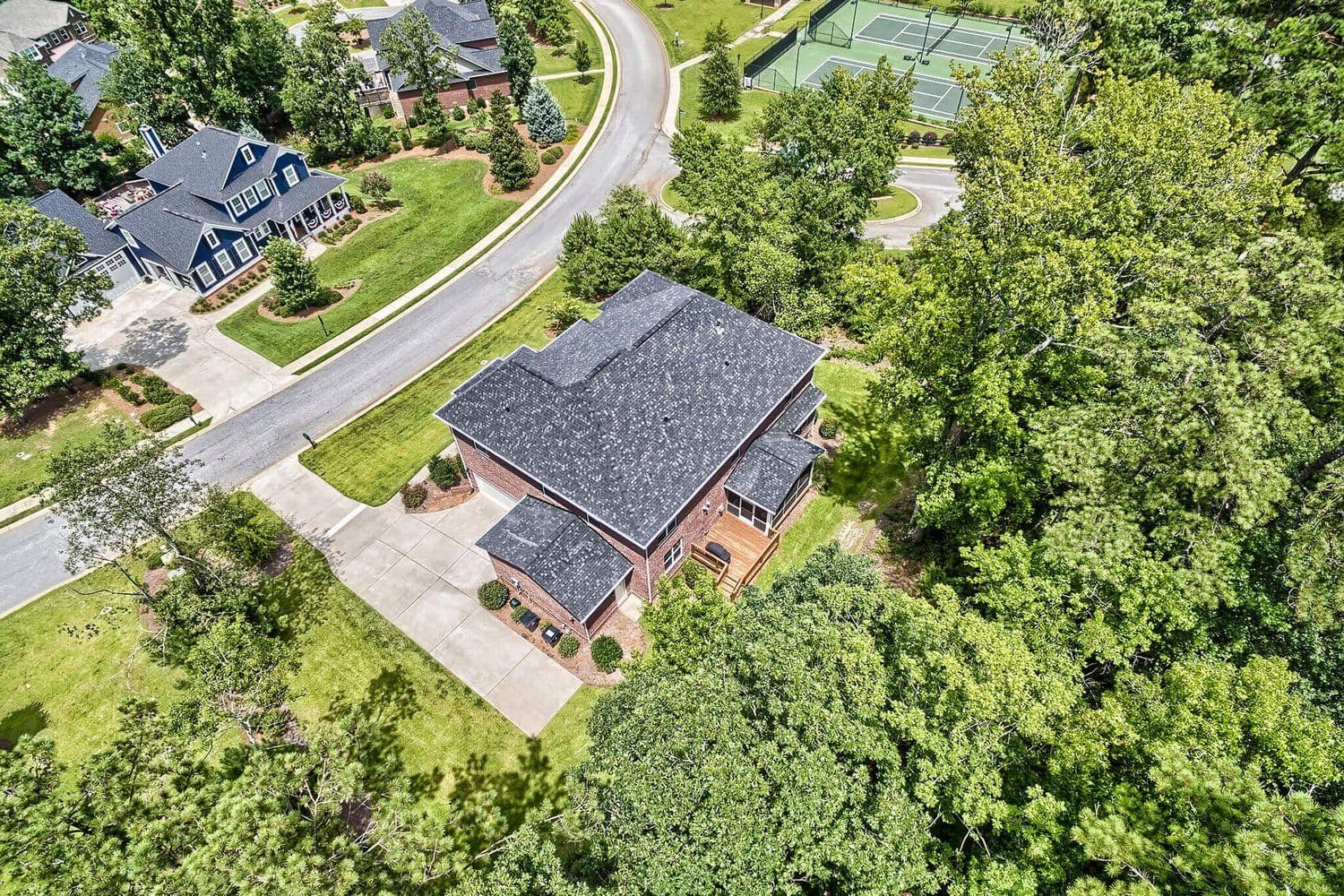 Aerial of a brick house with a side-loading garage among mature trees