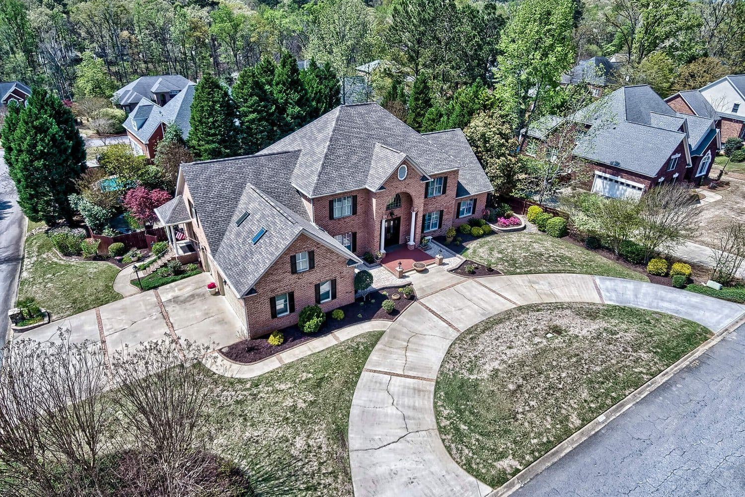 Aerial of a multi-level brick house with a curved driveway