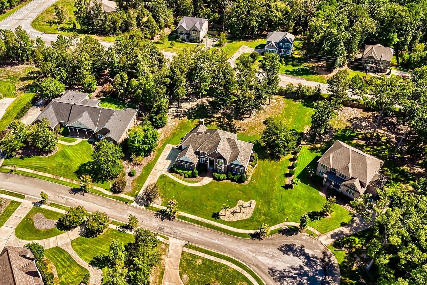 Aerial of a neighborhood with large homes and dense trees