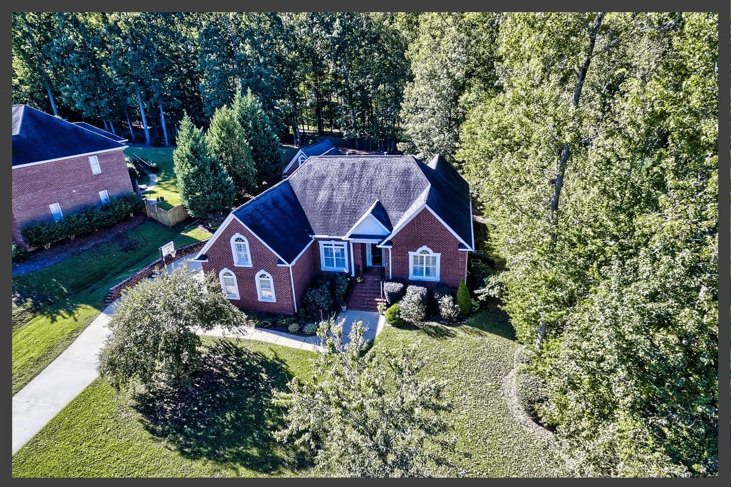 Aerial view of a brick house nestled in a dense green forest