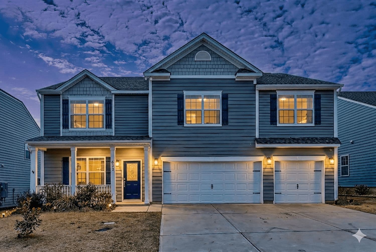 Dark blue two-story house at dusk with glowing windows