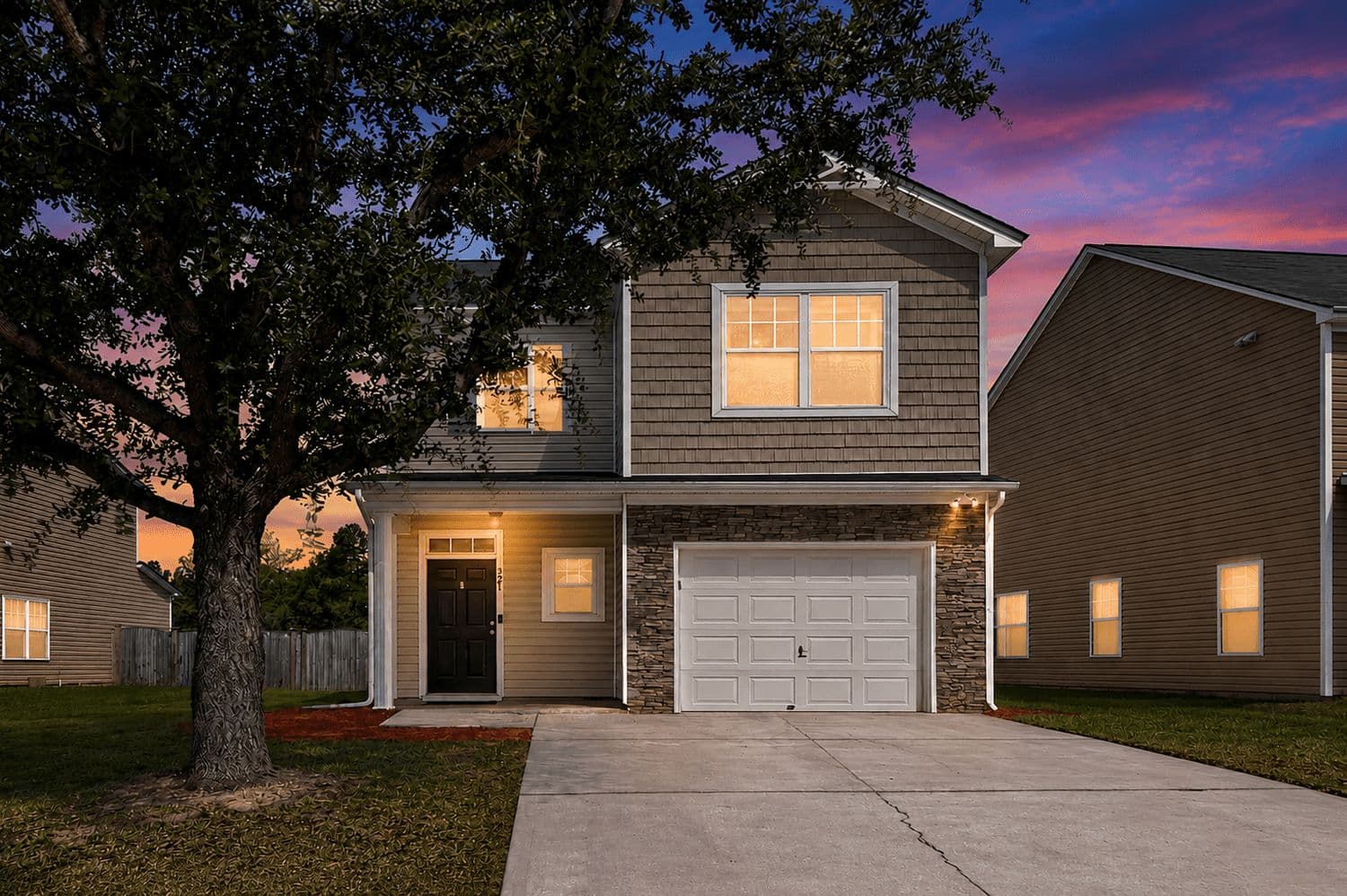Grey two-story house at dusk with a lit garage