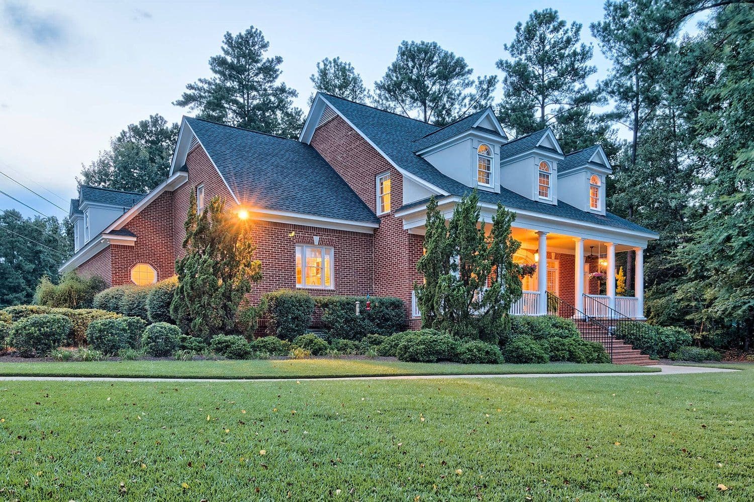 Large brick house at twilight with warm light in the windows