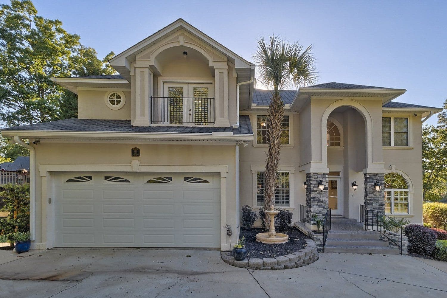 Light gray craftsman home with a three-car garage, stone columns, and a covered porch