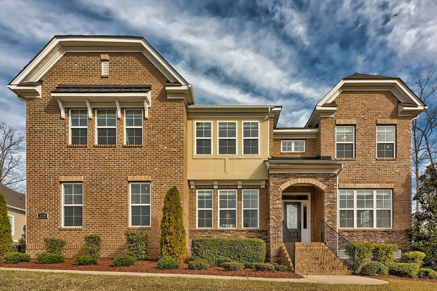 Modern two-story home with brick and light siding and multiple gables