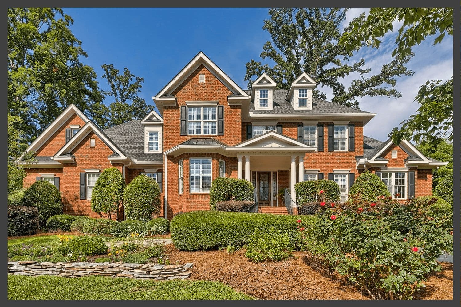 Multi-gabled red brick house with landscaped beds