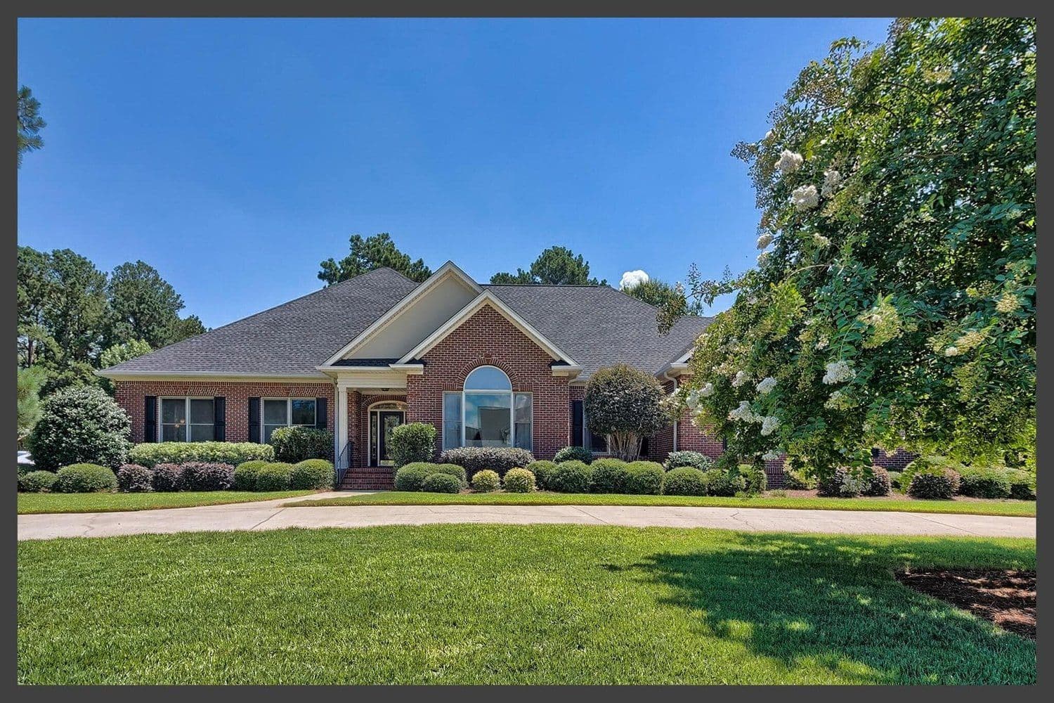 One-story brick home with a wide driveway and shaded front lawn