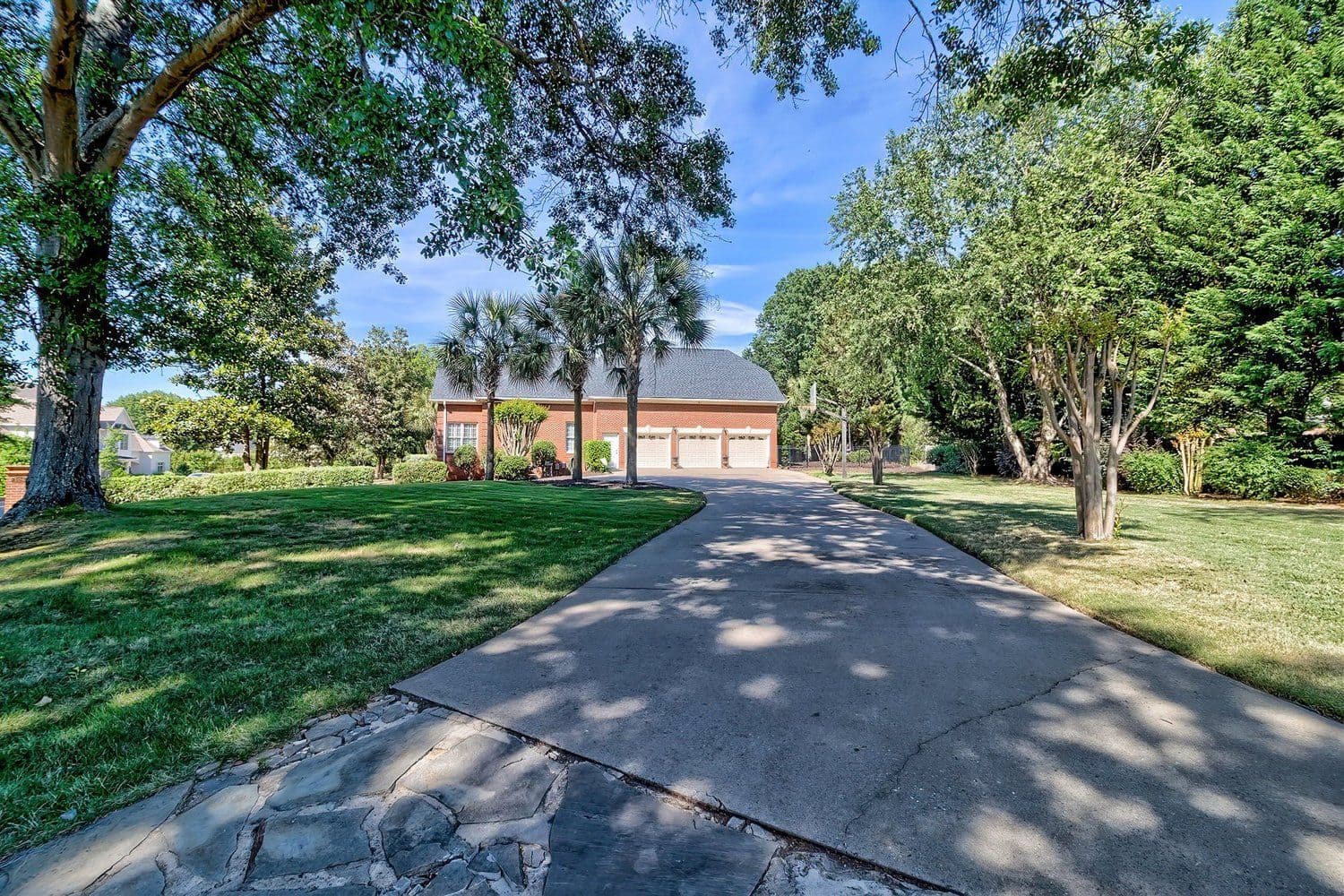 Paved driveway leading to a house flanked by mature trees