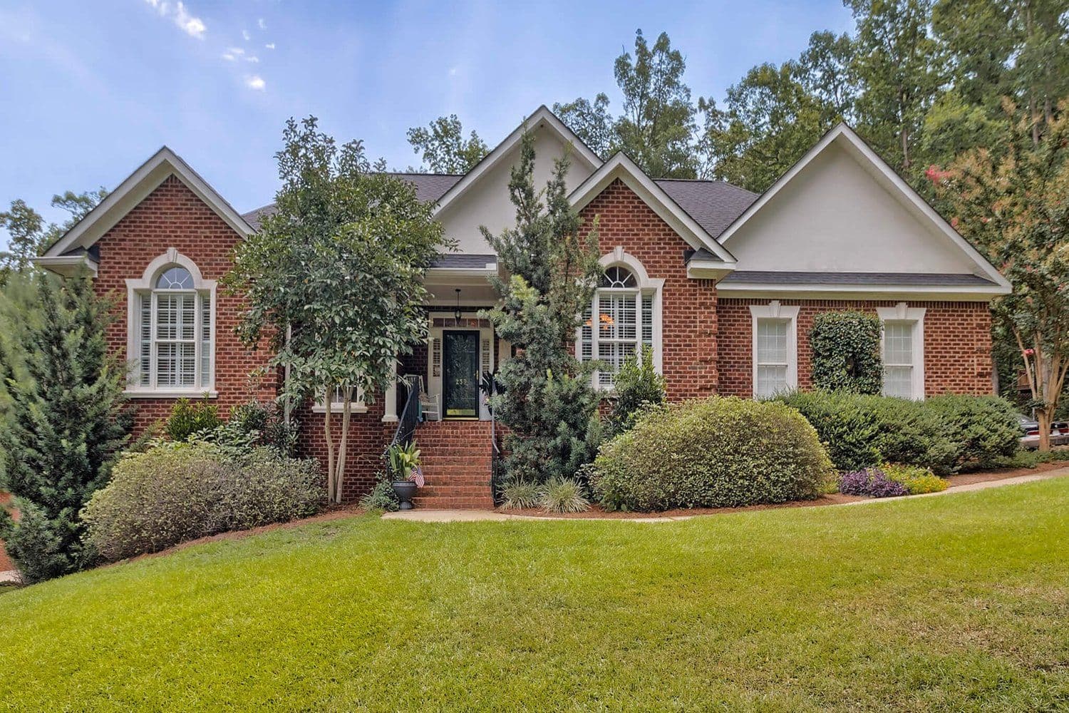 Red brick home with white gables and a manicured lawn