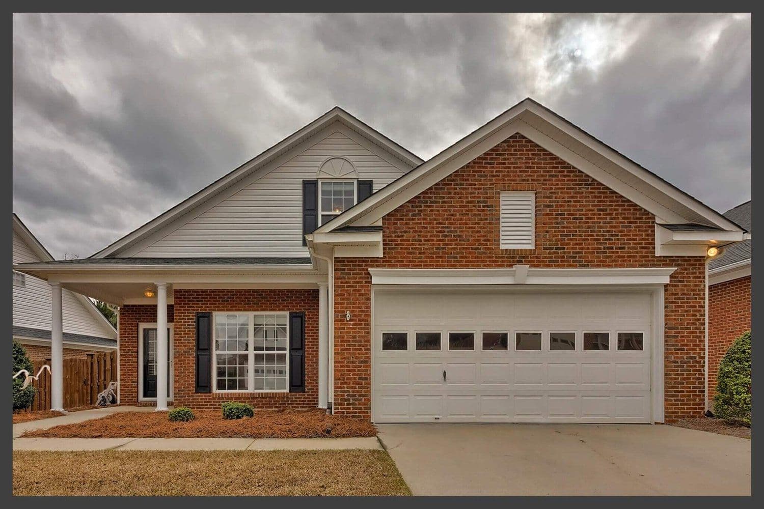 Red brick suburban home with white upper gables and a two-car garage