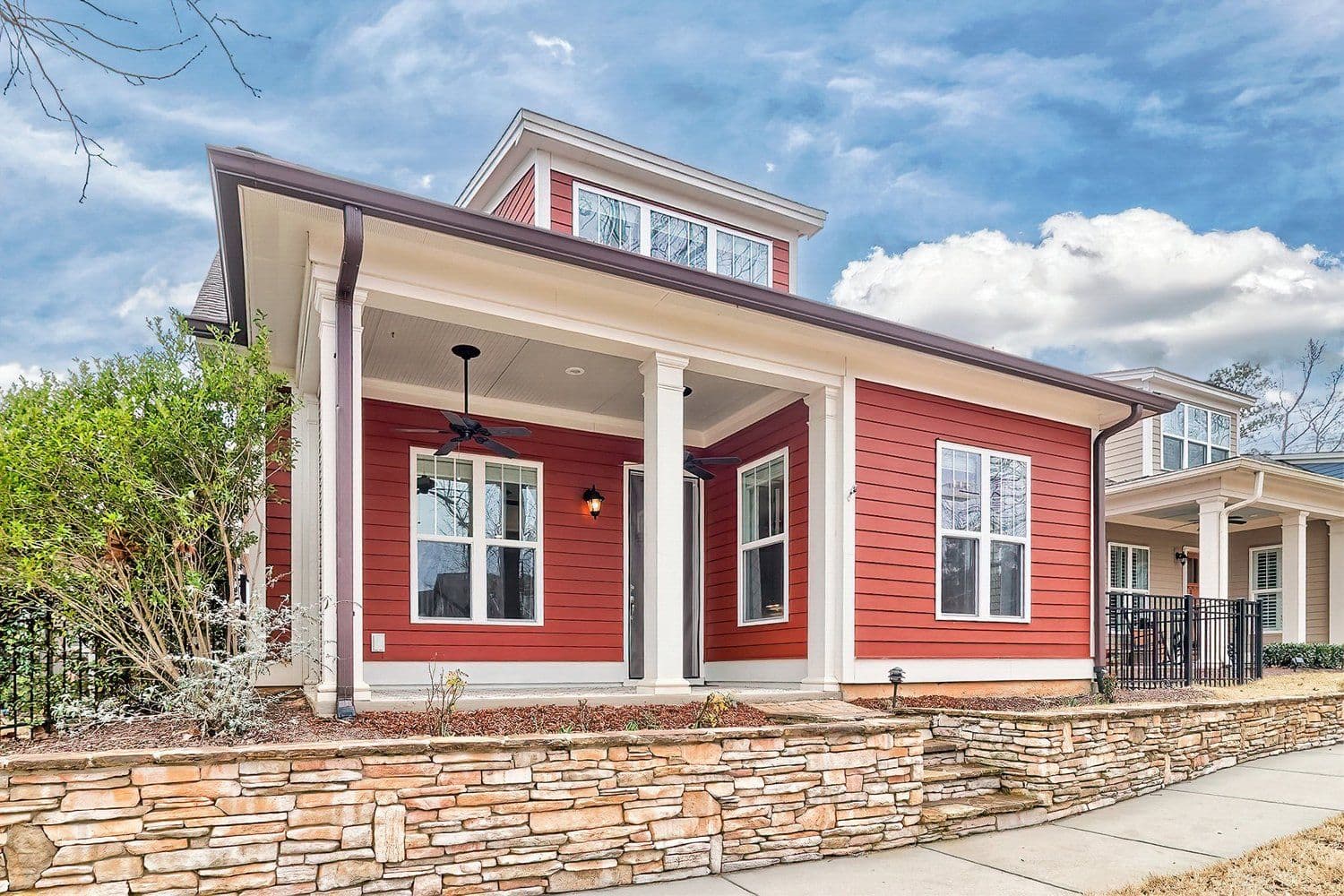 Red house with white trim and a stone retaining wall