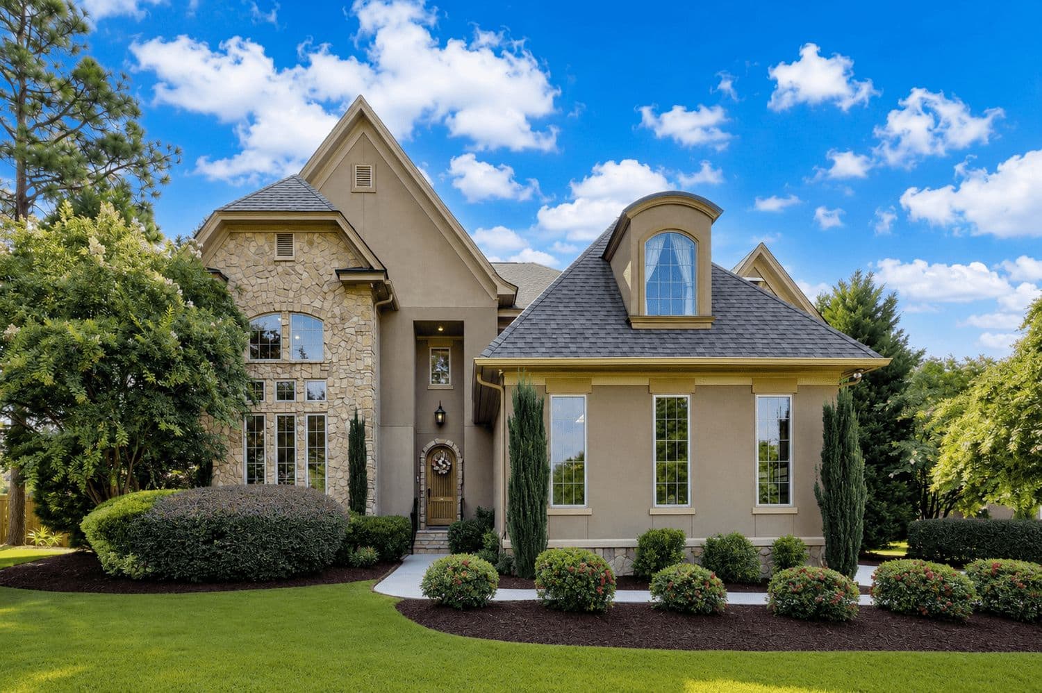 Tan stone and siding home with large windows