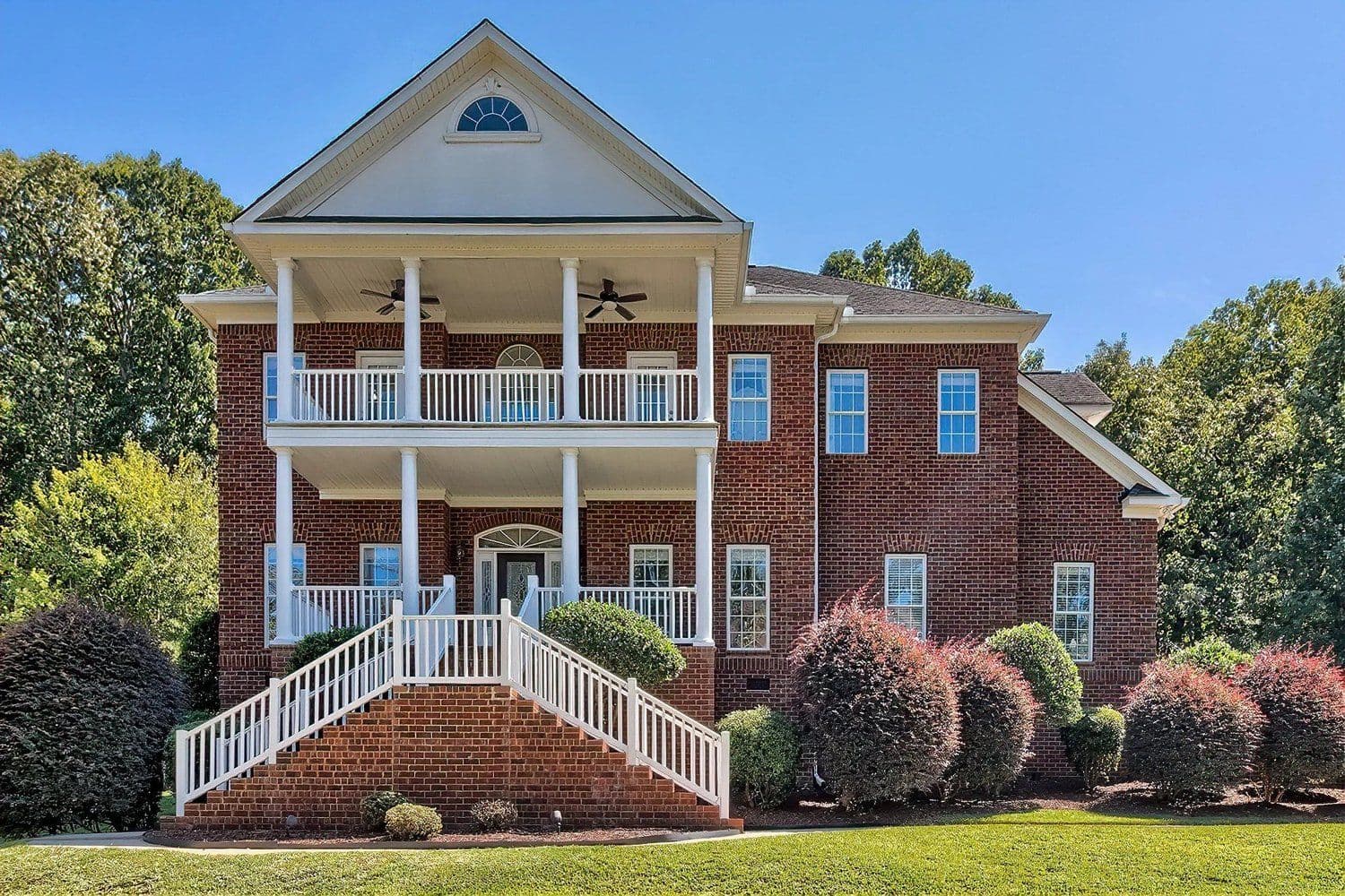 Three-story red brick home with stacked white porches
