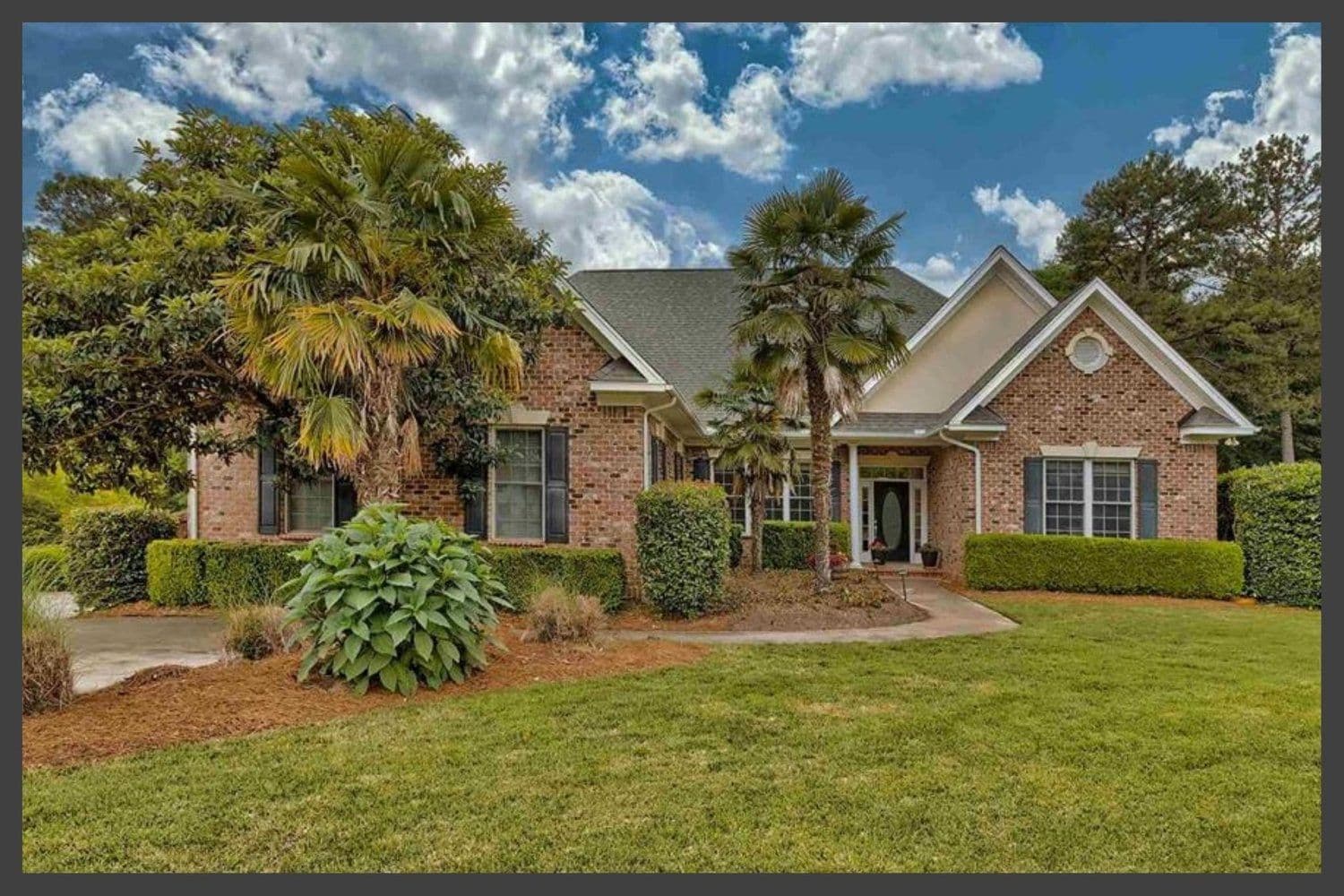 Two-story brick home with a two-car garage and mature trees