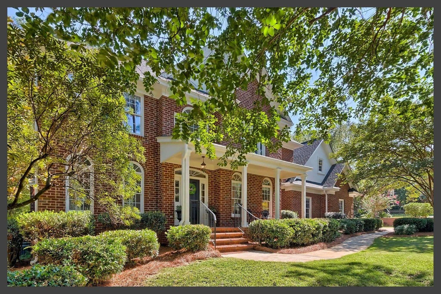 Two-story brick house with white columns on a wide front porch