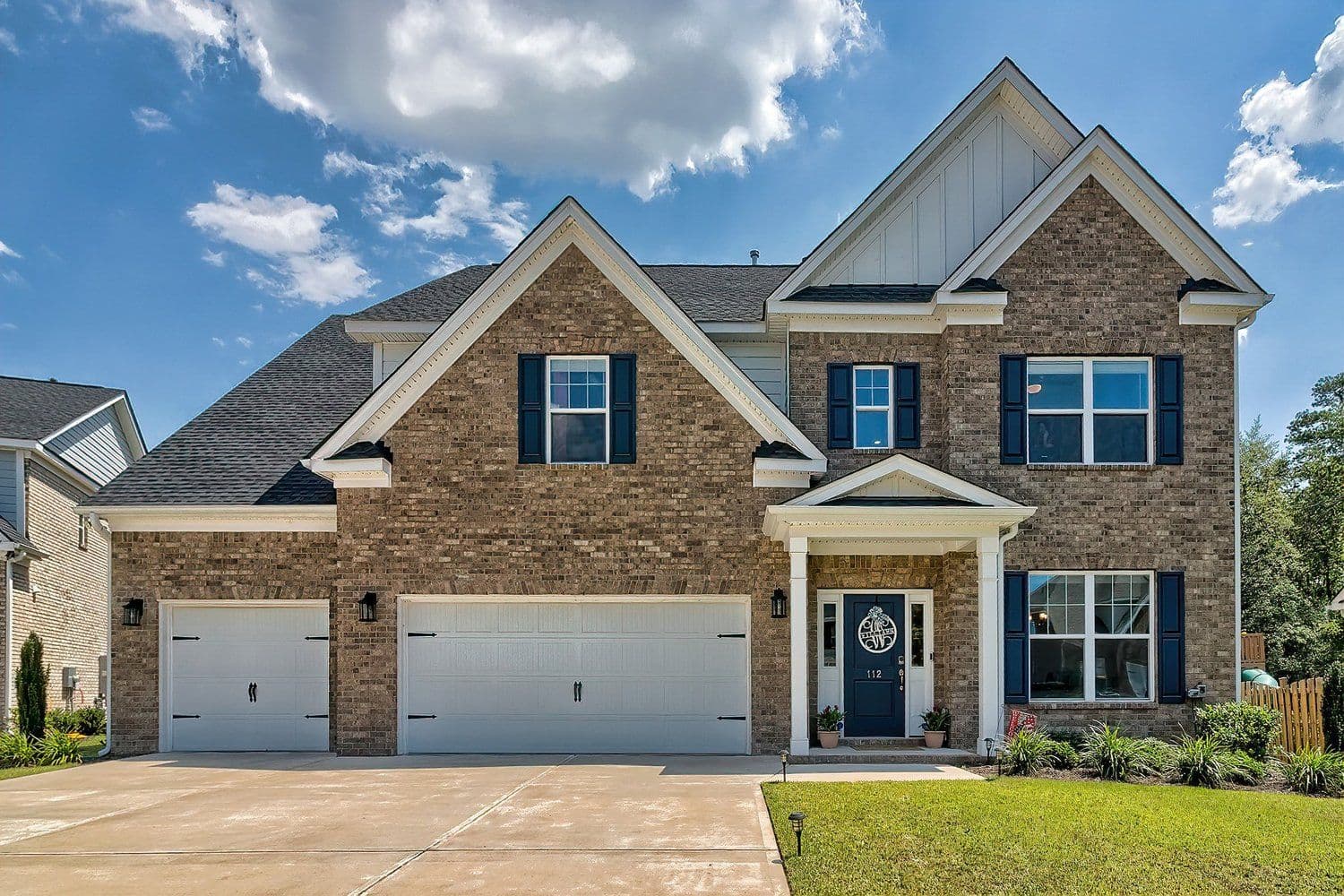 Two-story craftsman home with stone and blue-grey siding and a three-car garage