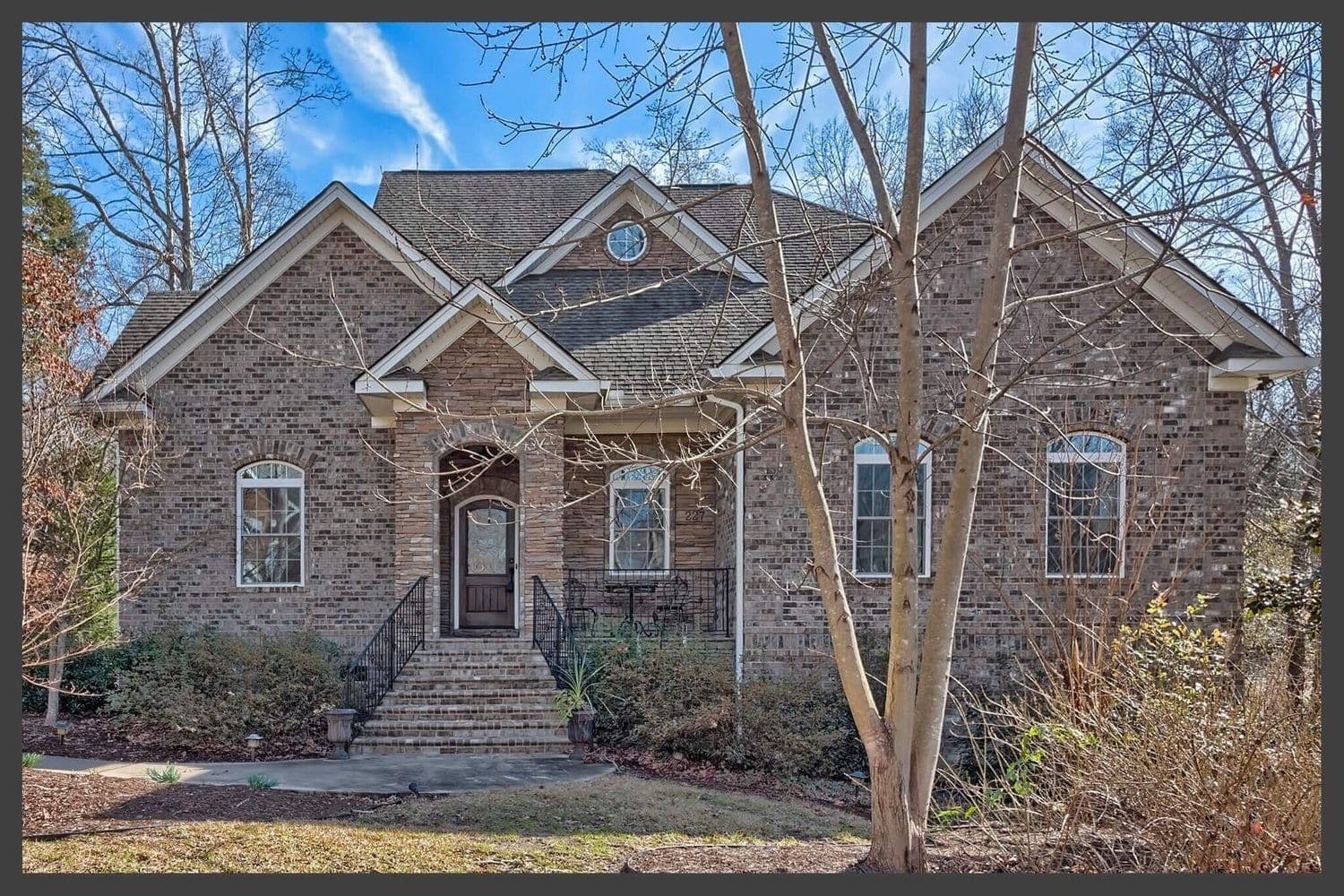 Two-story home with a tan stone facade and multiple gables