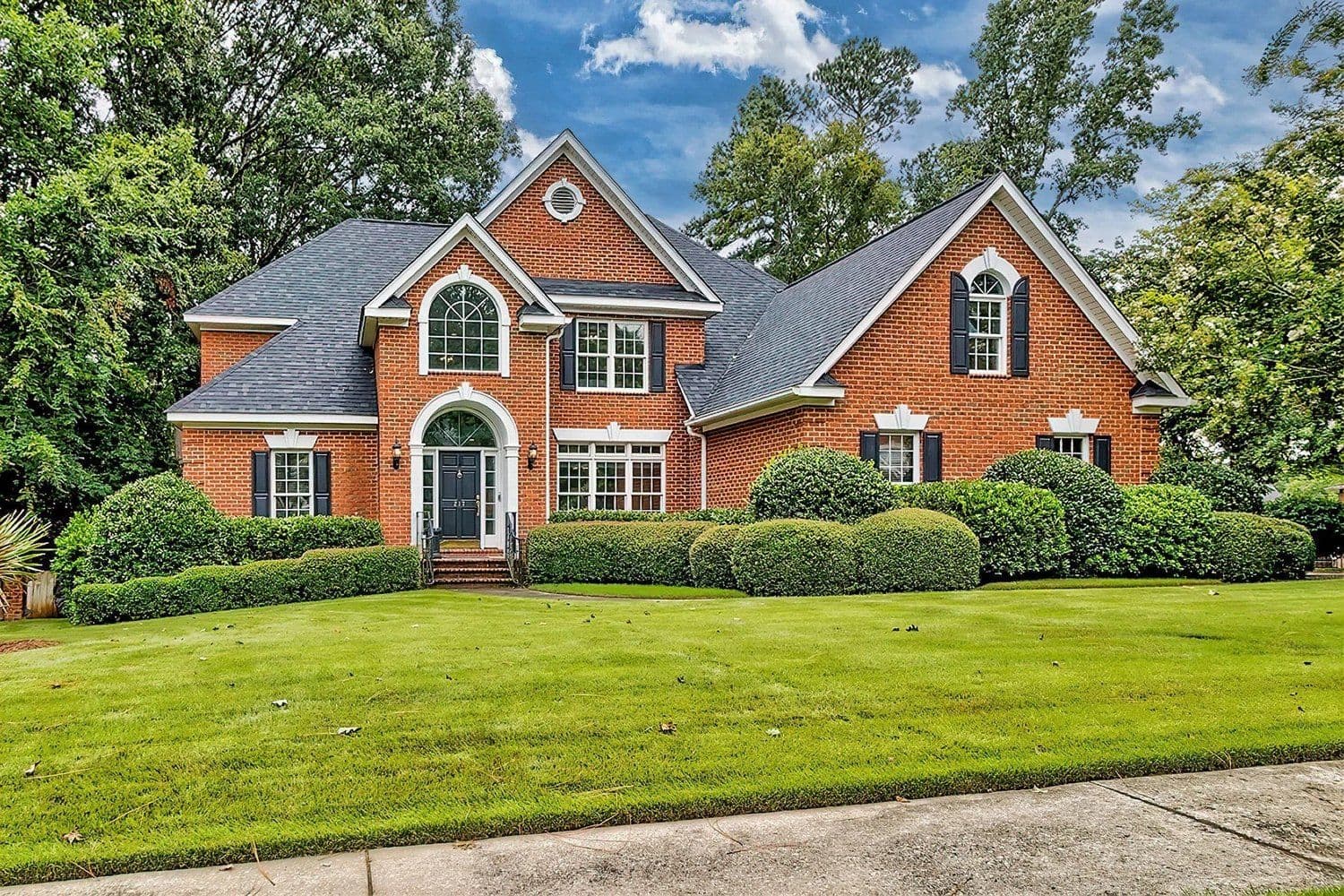 Two-story red brick home with arched windows