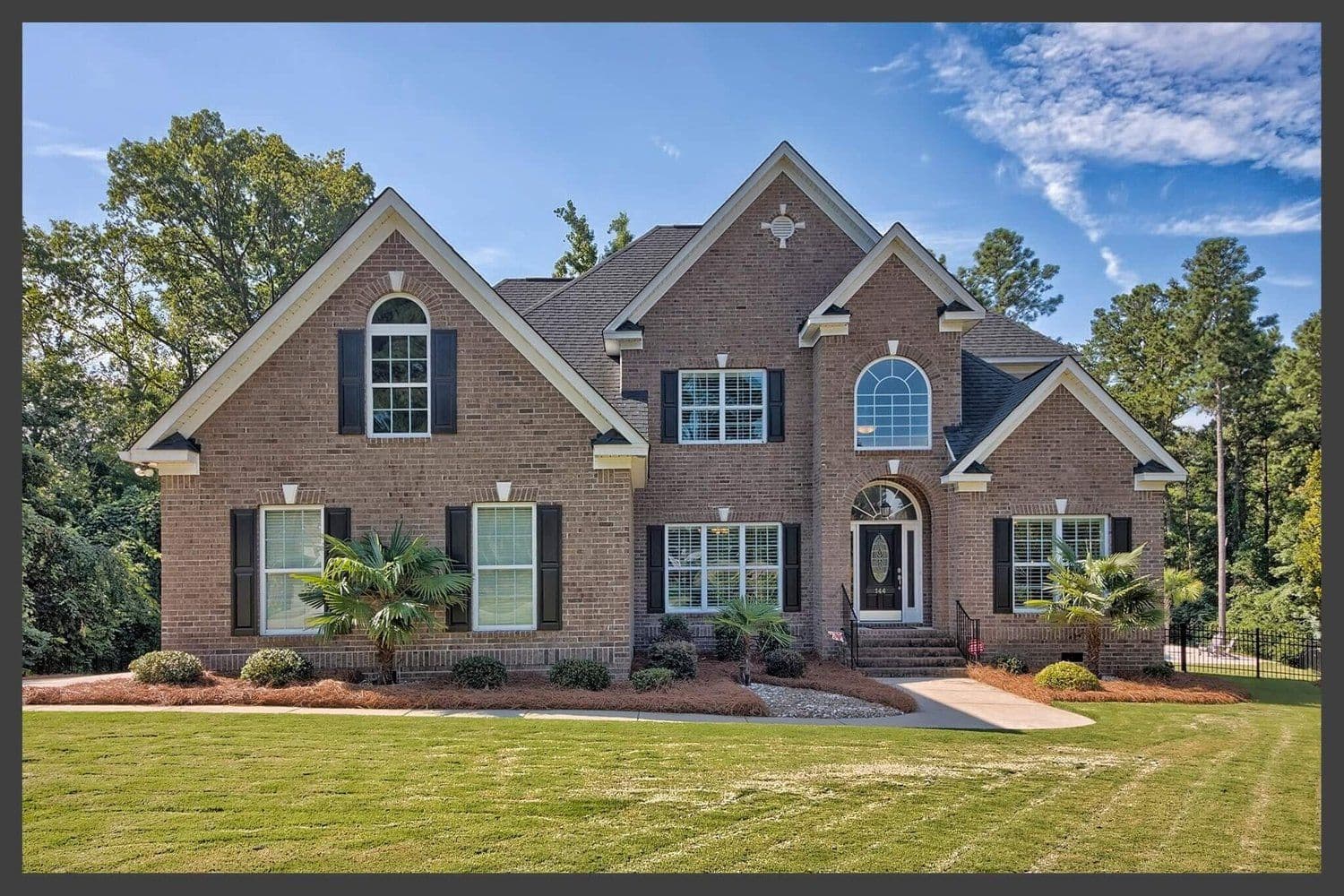 Two-story red brick house with black shutters and a white front door