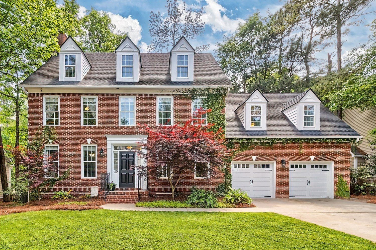 Two-story red brick house with green shutters