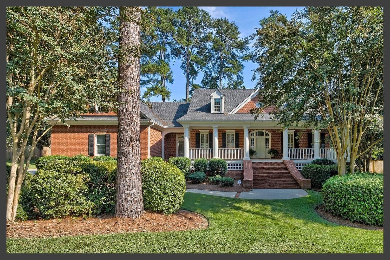 Wide single-story brick ranch home with a long front porch