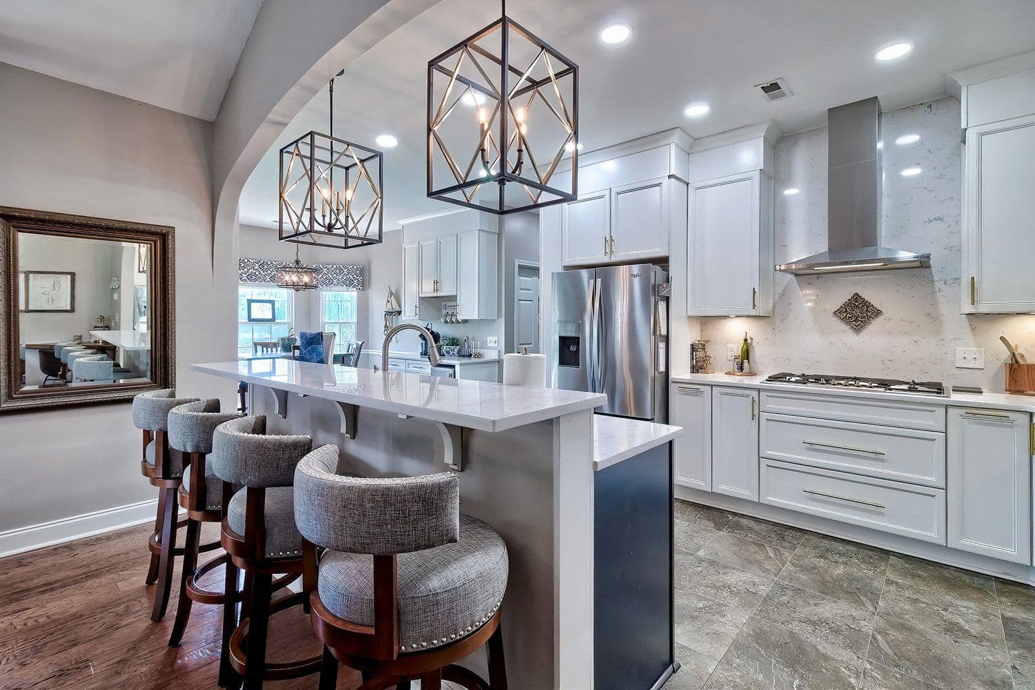 Bright kitchen with white cabinetry, grey island and three black pendant lights