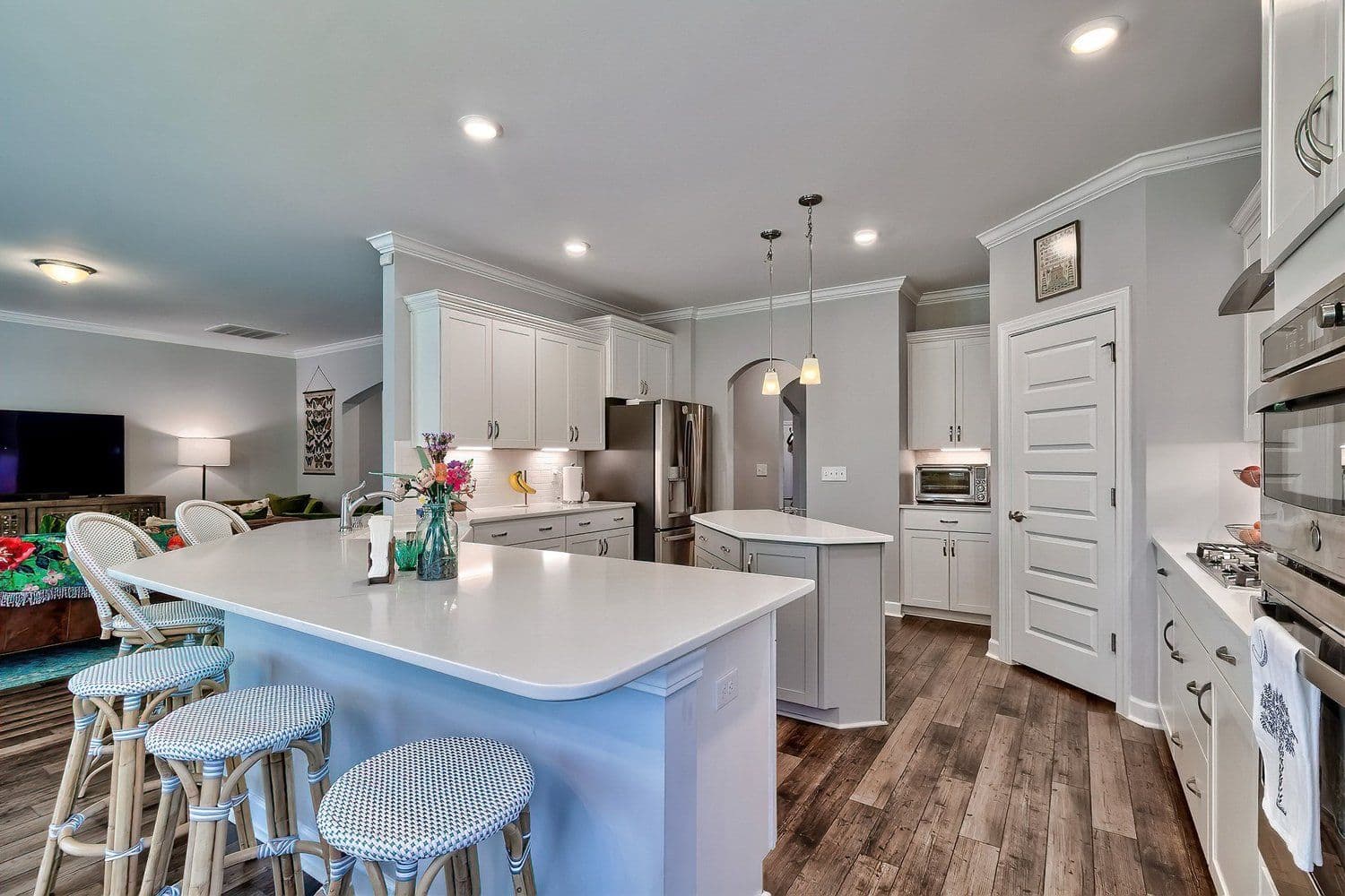 Open-concept kitchen with white cabinetry and a large grey island with seating