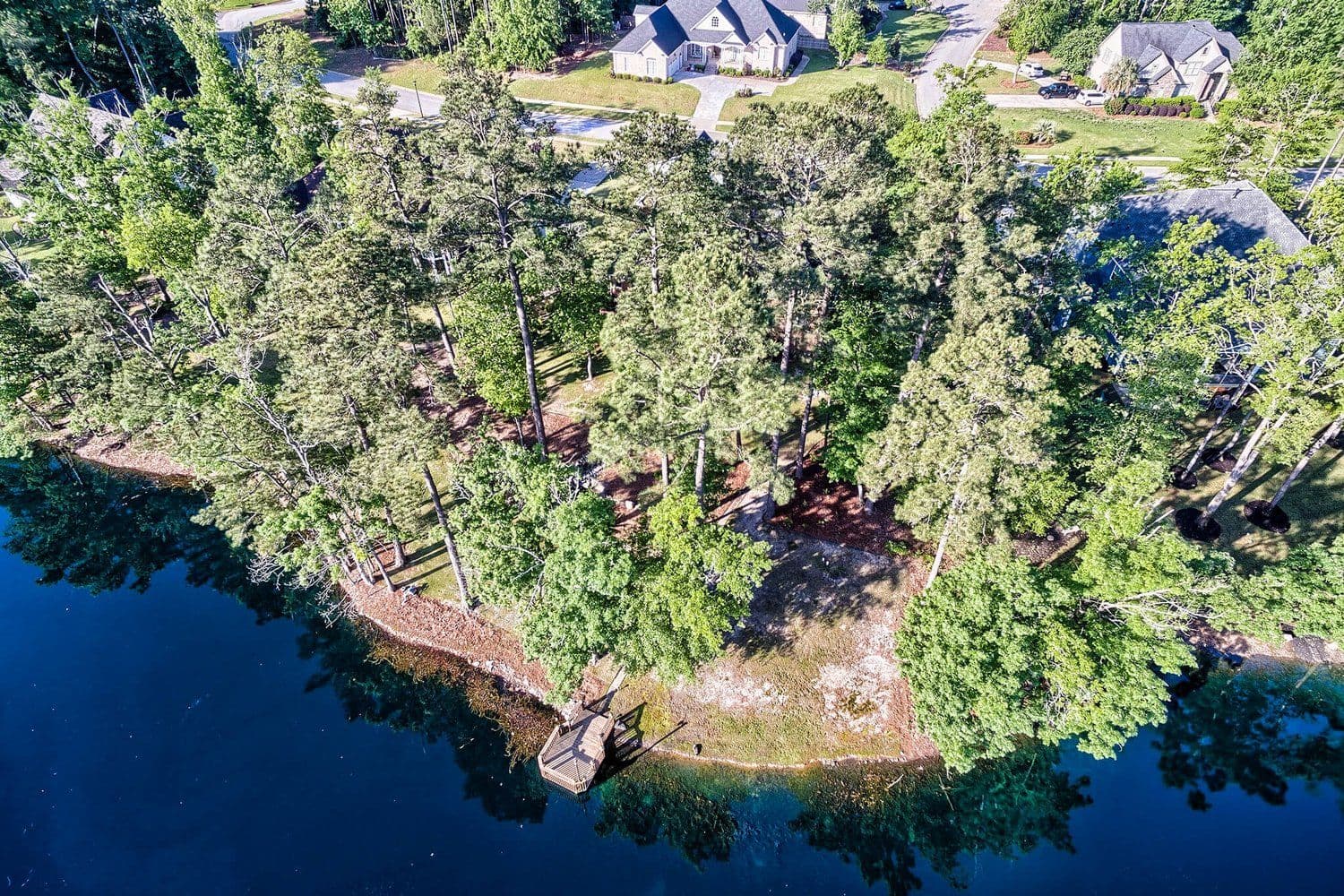 Aerial of a wooded peninsula with private boat docks along the shoreline
