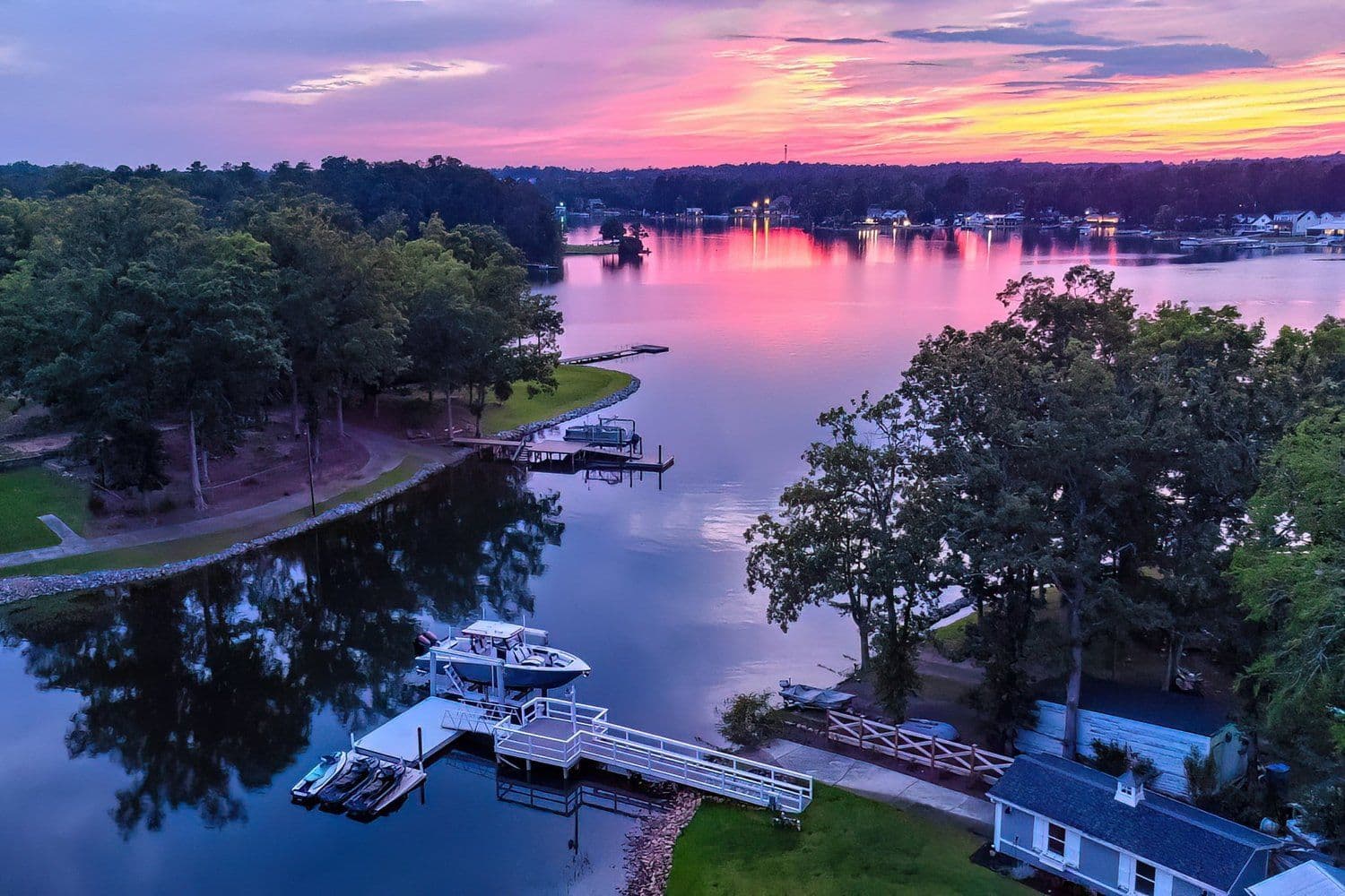 Aerial view of a lake at sunset with a boat dock and forested shoreline