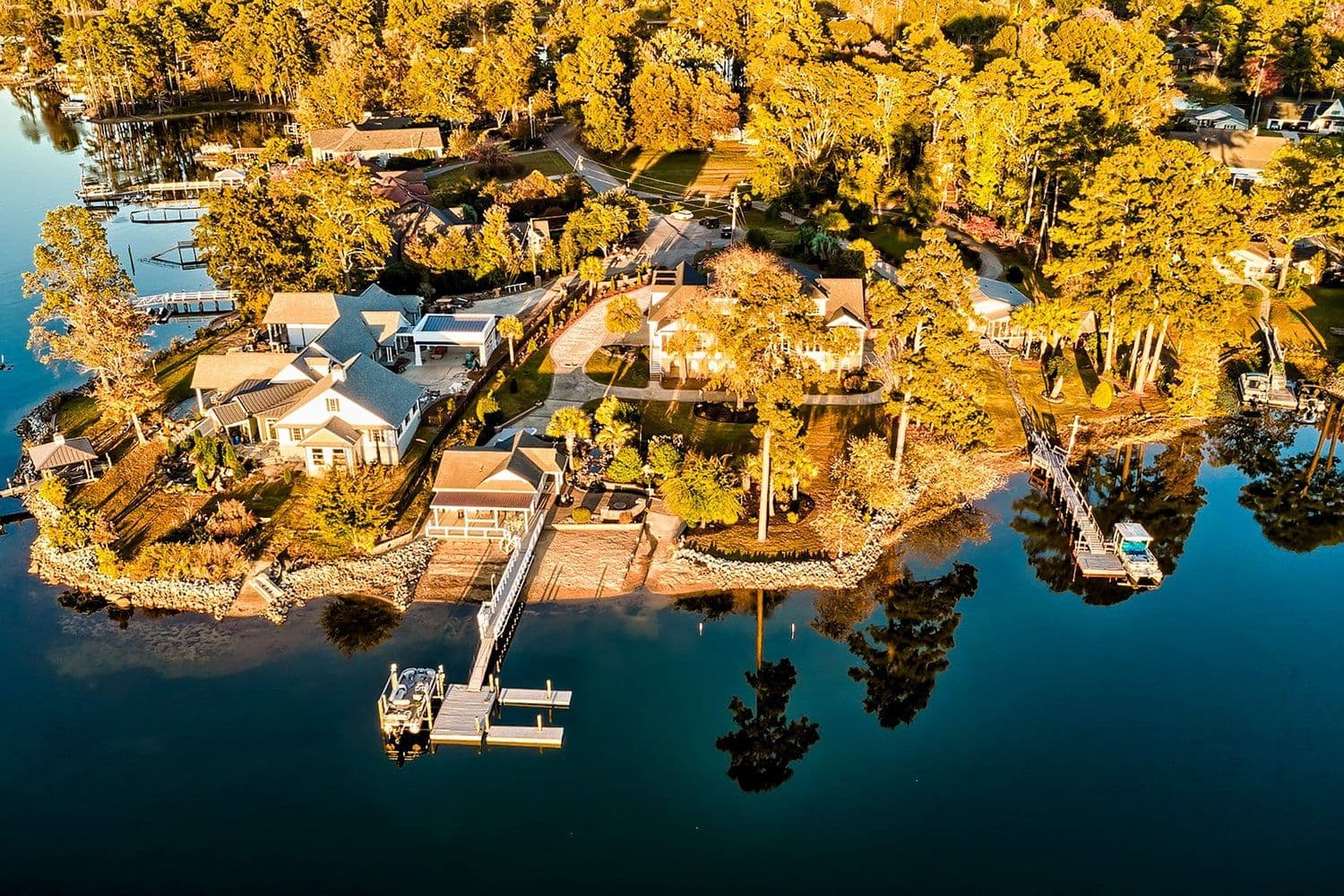 Autumn aerial of a lakefront house on a point with a long wooden dock