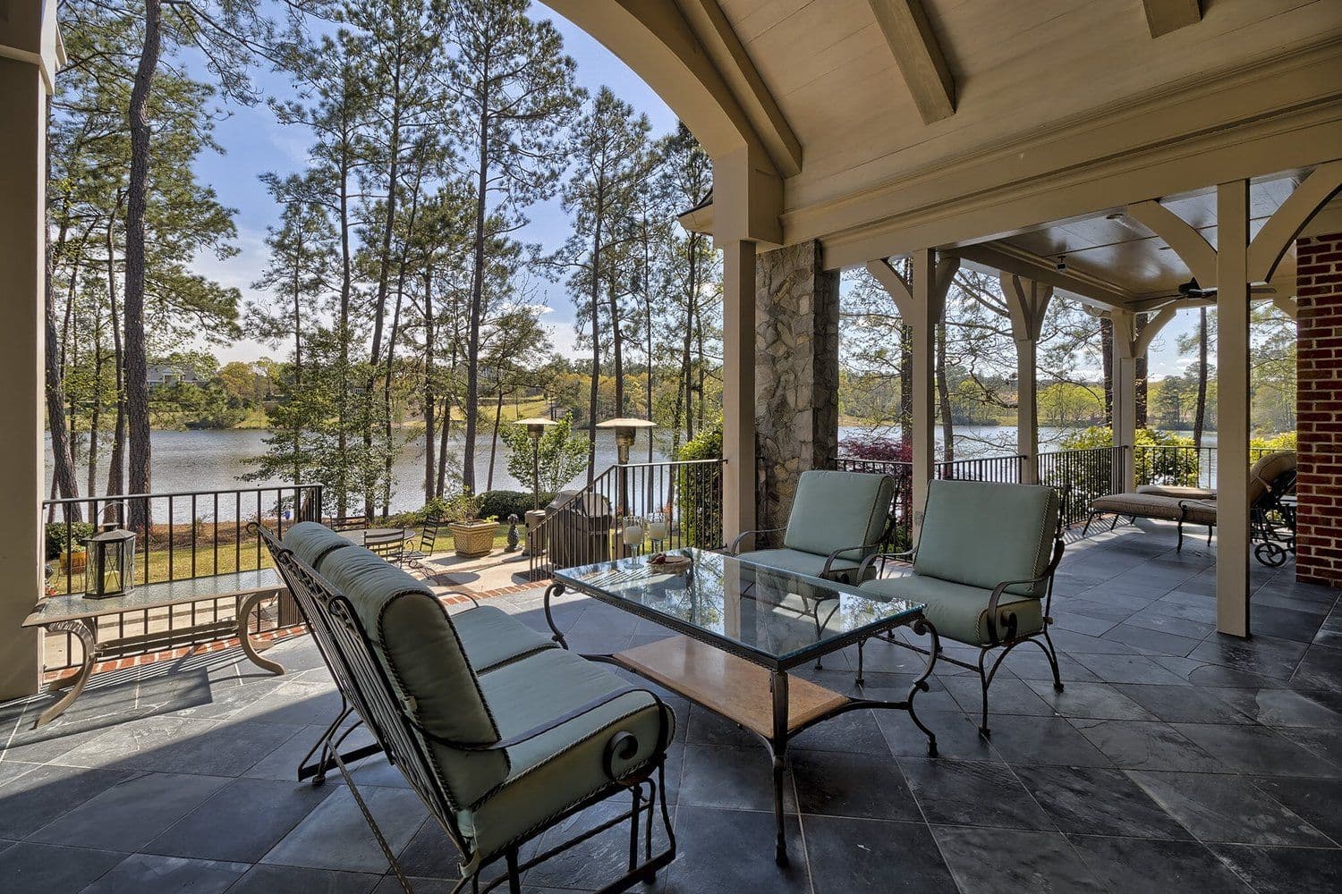 Covered stone patio with cushioned seating and open arches facing the lake