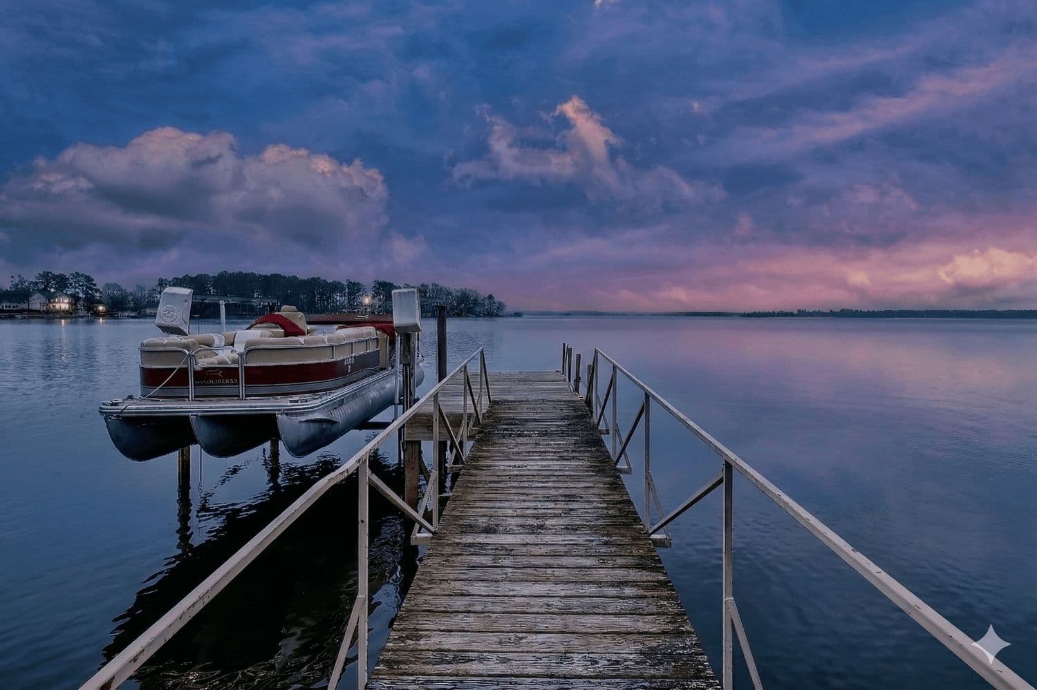 Dock at dusk with a pontoon boat moored in still pink and blue water