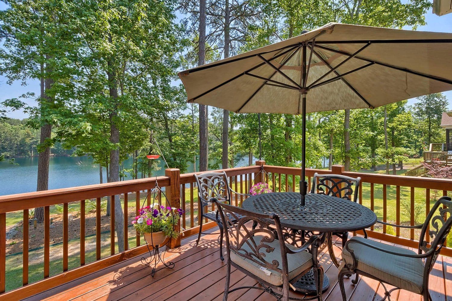 Elevated wooden deck with a patio set and umbrella overlooking the lake