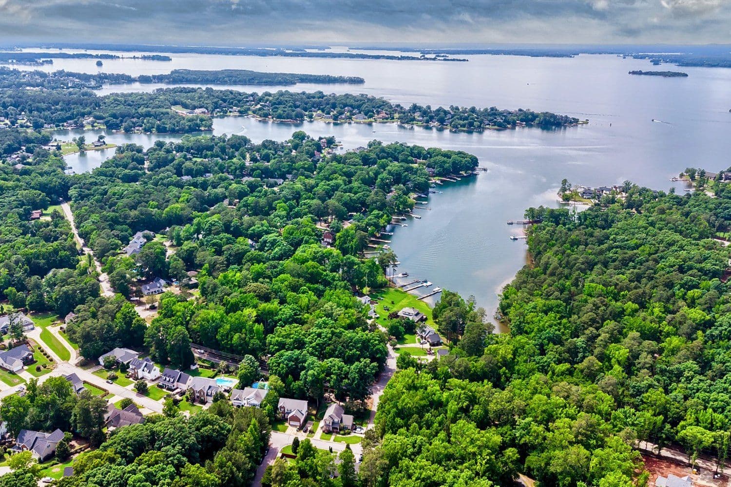 High aerial drone view of a lush green peninsula surrounded by water