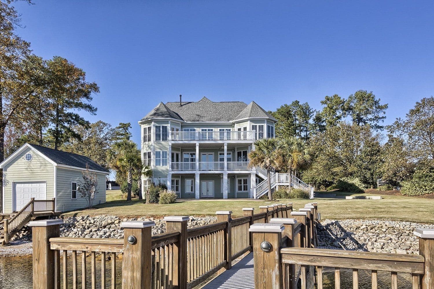 Large grey lakeside house seen from a boardwalk near the water