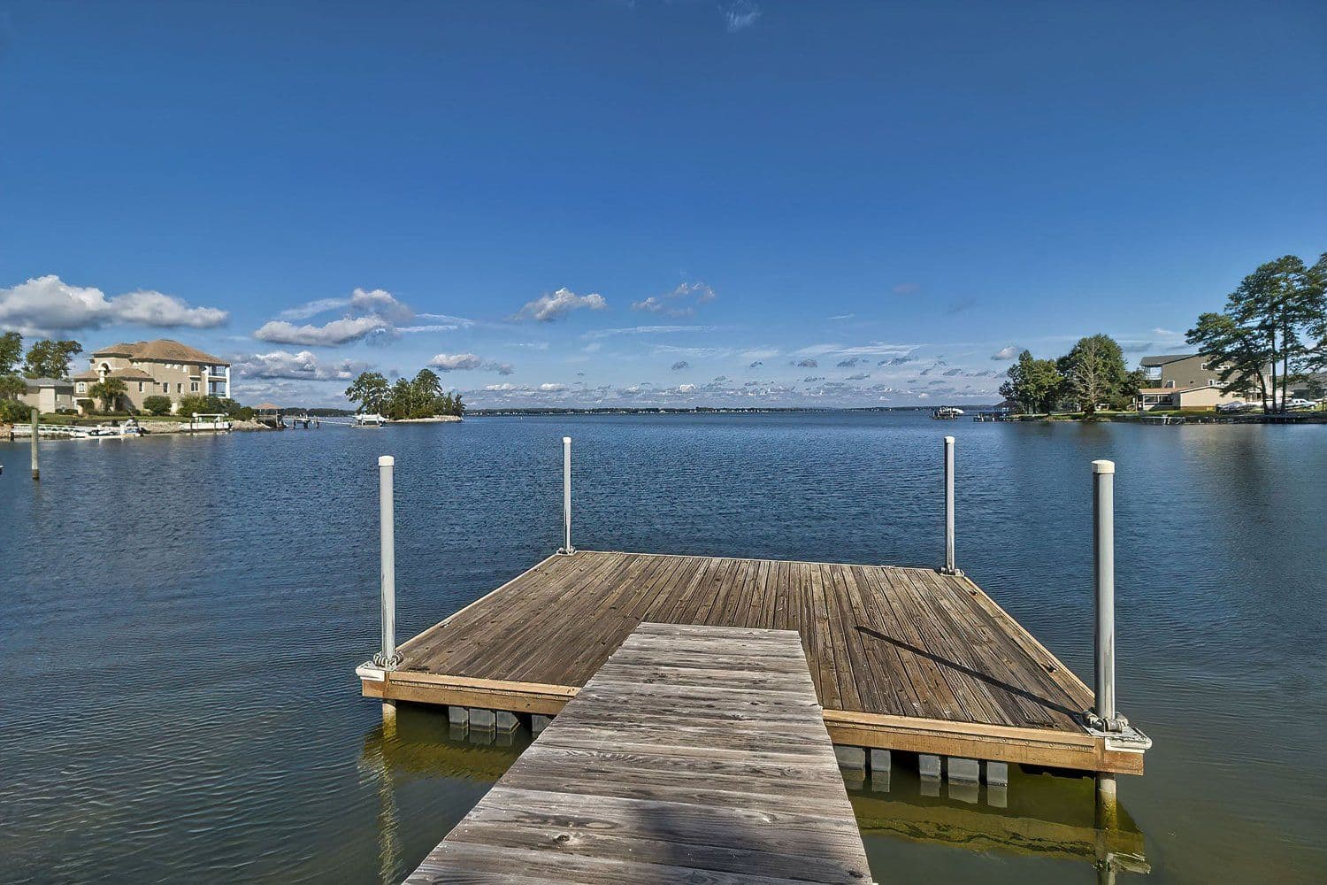 Wooden dock on a wide lake under a blue sky, seen from the walkway