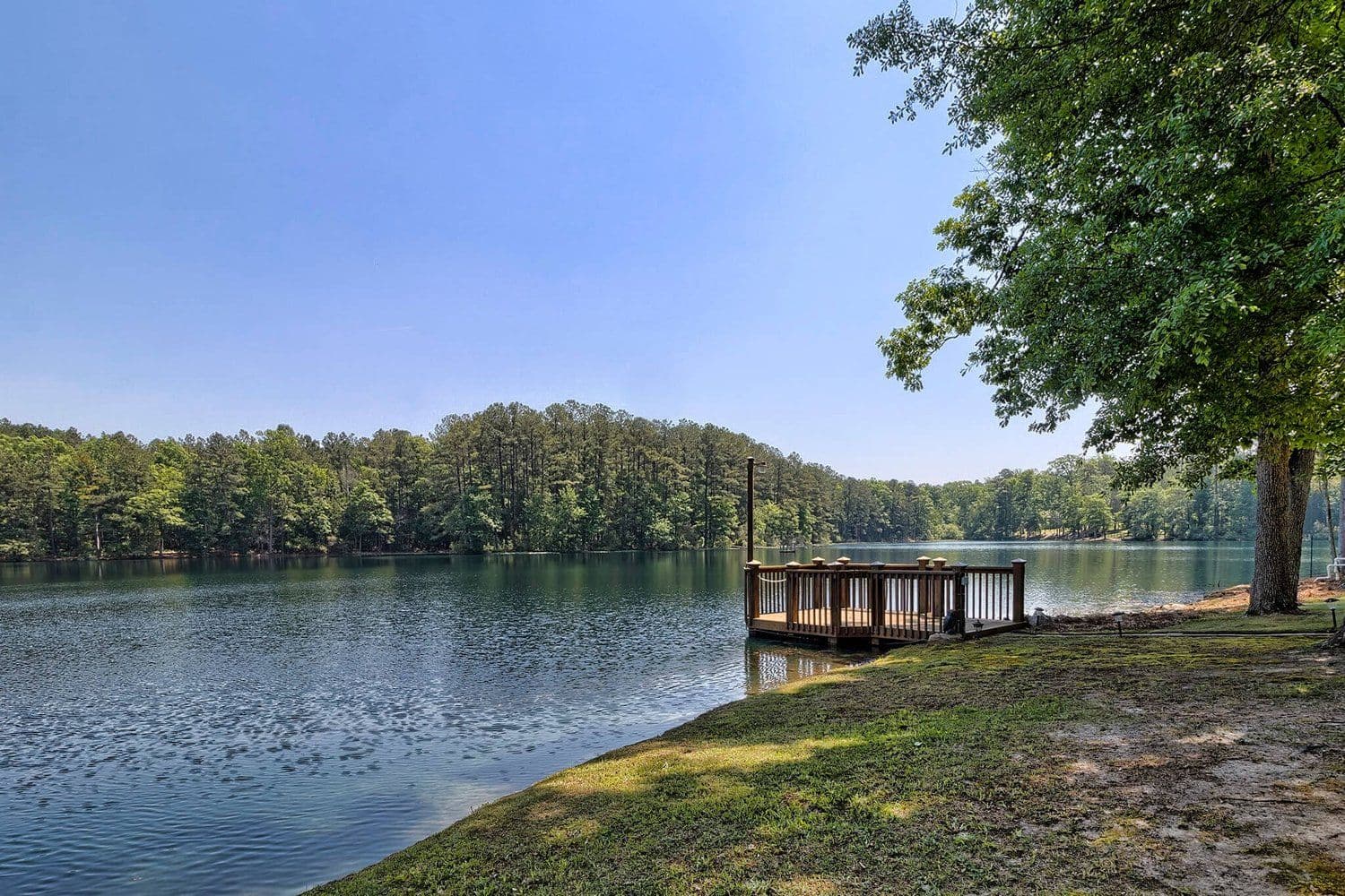 Small wooden dock extending into a quiet lake framed by trees