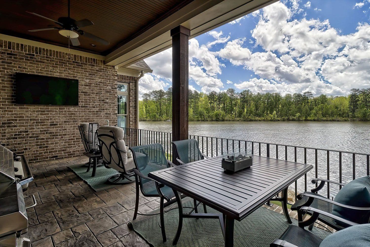 Stone-tiled covered patio with a dining table overlooking the lake