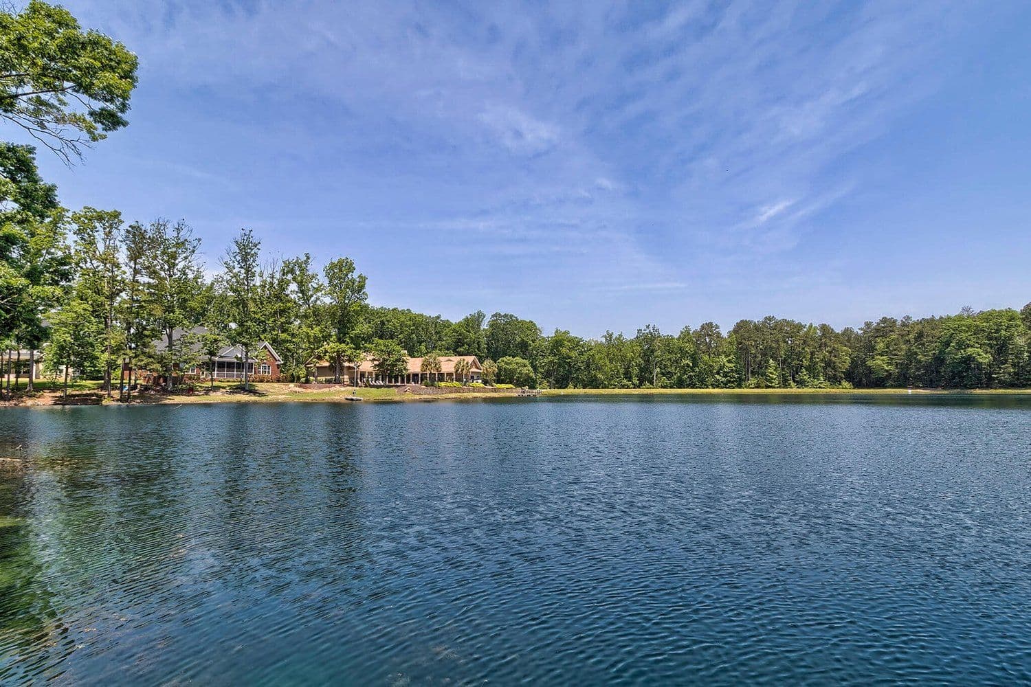Wide calm lake reflecting a blue sky with a tree-lined far bank