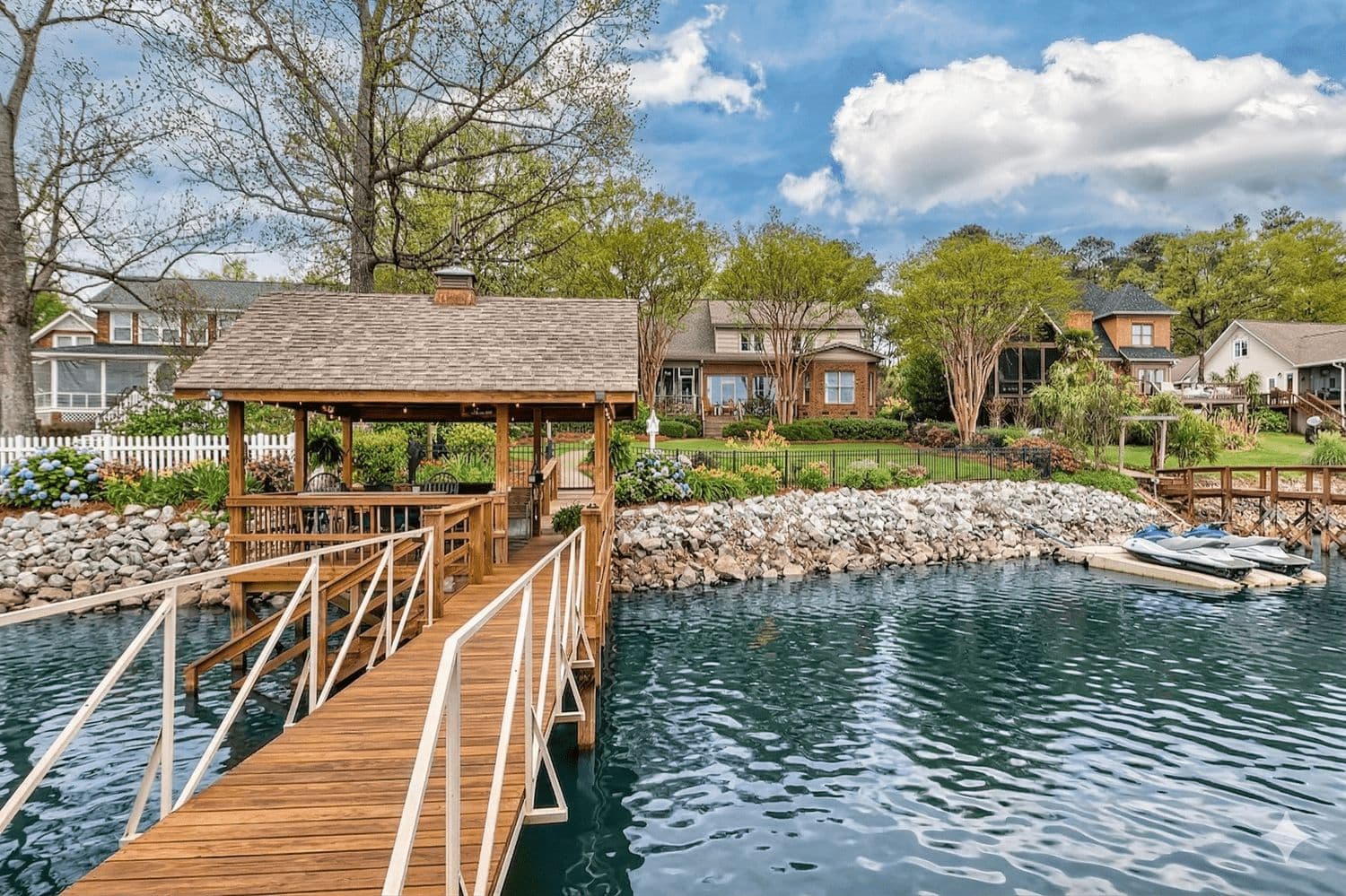 Wooden dock and pier extending into the water with upscale homes on the far shore