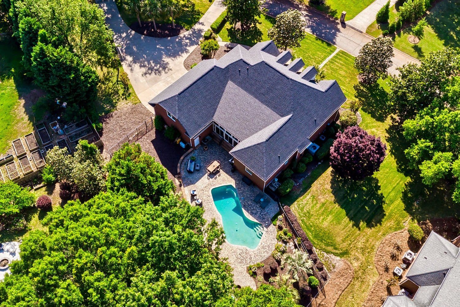 Aerial drone view of a brick home, pool and lawn