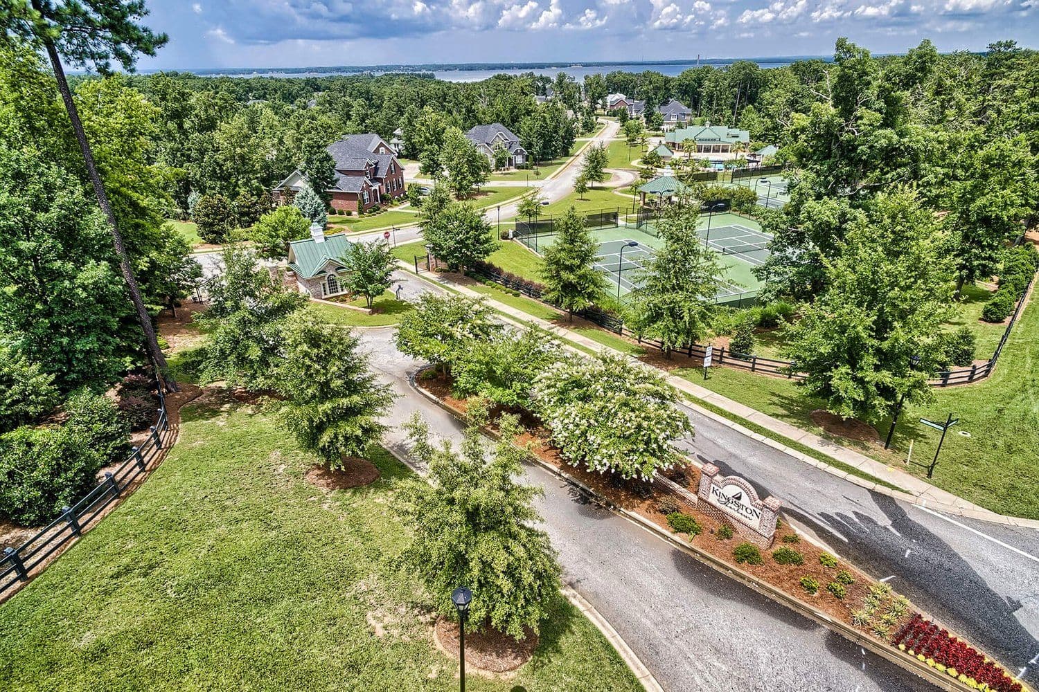 Aerial of a neighborhood with winding road, green space and tennis courts