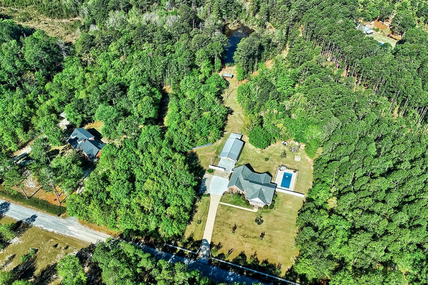Aerial of a single house and pool surrounded by dense forest